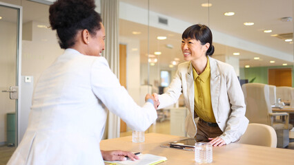 Fototapeta premium Japanese businesswoman welcoming her female business partner at the start of their business meeting