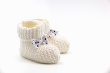 White crochet baby booties with black polka dot bows isolated on a white background. Handmade baby...