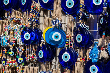 Nazar in market. Blue and red Fatima eye close-up protective amulet against evil eye. Israeli and turkish souvenir. decorative glass blue souvenirs in the form of an eye.