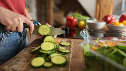 Woman Cutting Cucumbers On A Cutting Board