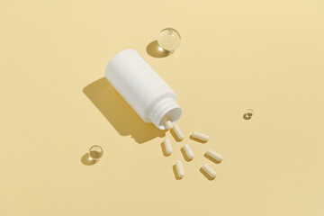 White mockup jar and spilled pills on yellow isolated background. Concept of natural dietary supplements, pharmacy and health care.