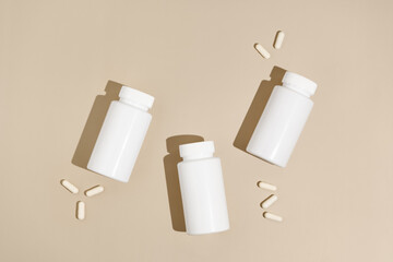 Three white mockup jars and pills capsules on beige isolated background. The concept of pharmacy, medicine, health, scientific medical research and supplements
