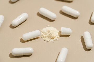 Pattern of white pills capsules and active substance in powder on beige isolated background. Concept of medicine, natural dietary supplements, health and antibiotics.