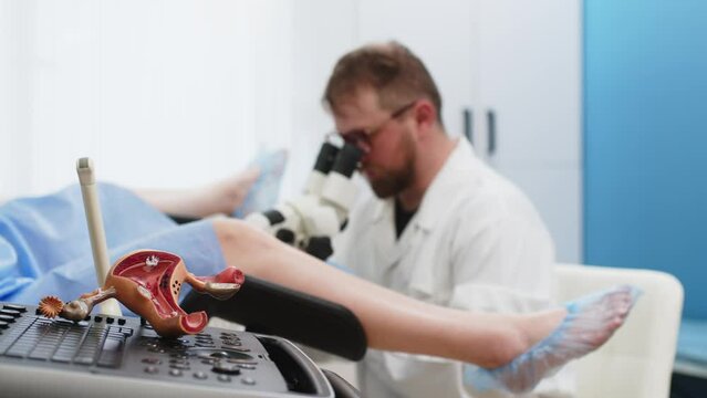 Doctor gynecologist showing patient female diseases on model of uterus and ovaries. A female patient sits in a gynecological chair during a consultation with the attending gynecologist in a hospital