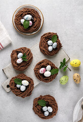 Easter chocolate cookies in the shape of Nests with sweet eggs with mint leaves on light table. top view.