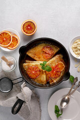 Crepes with Orange Sauce in a cast iron pan. Traditional French crepe Suzette with orange sauce. Flat lay, top view, copy space