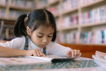 A young girl is reading a book in a library