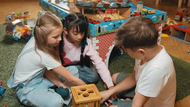 Multicultural smart students playing wooden block together at playroom of kindergarten. Diverse children play toy to improve creativity and imaginary. Creative activity education concept. Erudition.