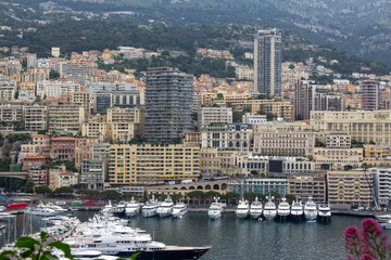An opulent view of Monte Carlo's marina, showcasing a row of extravagant yachts moored against a backdrop of densely packed, upscale residences