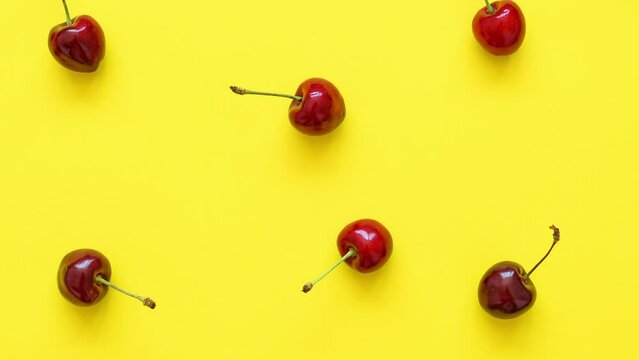 Video background of big sweet cherries on a bright yellow background. Sweet cherries close up video. Summer flat lay berry background. Top view on cherry pattern