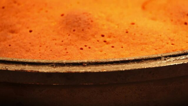 Sponge cake in a black frying pan is rotated in a circle on the table.