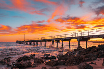 Robe pier with fishermen during early morning sunrise viewed from the shore, Limestone Coast, South Australia