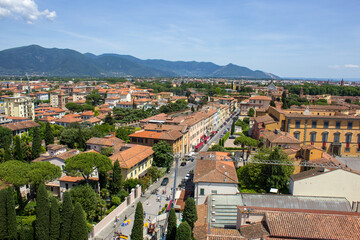 The vibrant green boulevards of Pisa align with the city's rustic architecture, set against the...