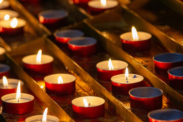 A serene display of red votive candles glowing warmly, the flickering flames offer a silent prayer...