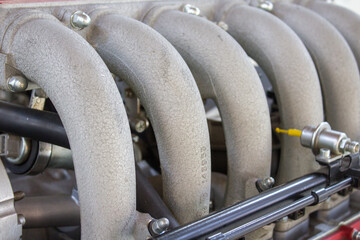 A close-up view of a car's intake manifold, highlighting the curved pipes that facilitate air...