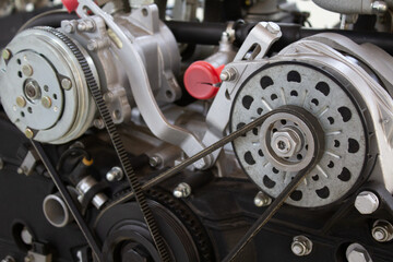 Close-up of a complex engine timing belt system, showcasing pulleys and gears on a black engine...