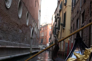 Wandcirkels tuinposter Intimate perspective from a gondola navigating a narrow, secluded canal in Venice, with historic brick buildings rising on either side. © Keifer