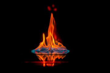 Intense flame, fire, burning brightly on a dark background, on a mirror surface with...