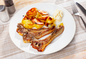Grilled lamb ribs with golden crust served with fried potatoes on plate. Traditional spanish dish...