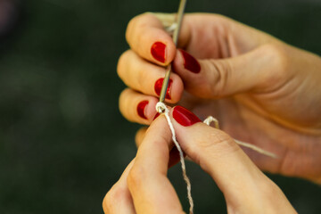 pair of hands with painted nails crocheting with needle and thread