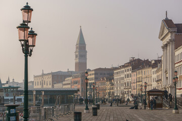 View from the waterfront Riva degli Schiavoni at the distant Tower of San Marco with Doge Palace on...