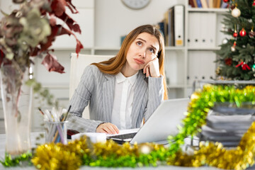 Tired businesswoman working with documents in business office during christmas