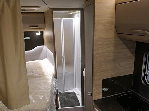 Bedroom and bathroom part of modern german camper van Knaus Van Ti Plus 700 LF, displayed on Caravan Bike Travel expo in Nitra, Slovakia, march 2024