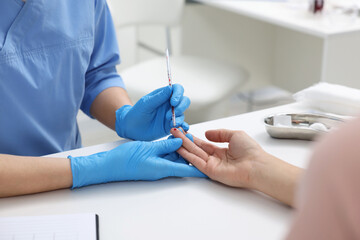 Laboratory testing. Doctor taking blood sample from patient at white table in hospital, closeup