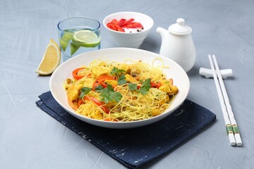 Stir-fry. Delicious cooked noodles with chicken and vegetables in bowl served on gray textured table