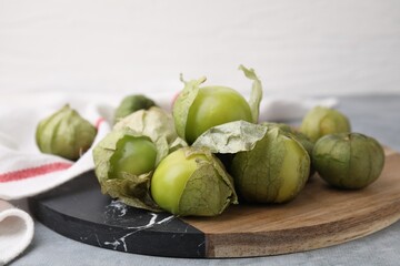 Fresh green tomatillos with husk on gray table, closeup