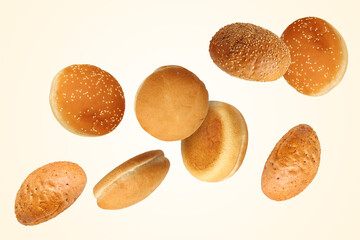 Fresh burger buns falling on beige background