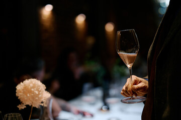 people hold glasses of white and red wine in a night restaurant, celebrating