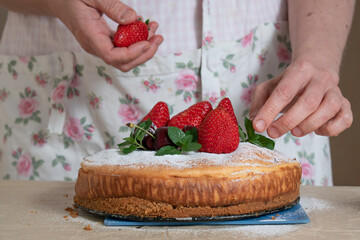 women's hands decorate the cake with berries and mint at studio