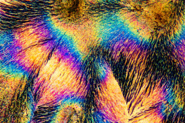 Extreme macro photograph of Vitamin C crystals forming abstract modern art patterns, when illuminated with polarized light, under a microscope objective with 50x magnification