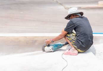 Worker cutting the concrete slab with electric circular saw and dust fly arround.