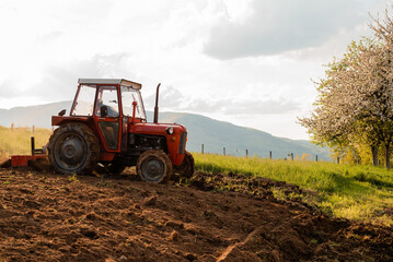 Tractor sowing crops at agricultural fields in spring.
