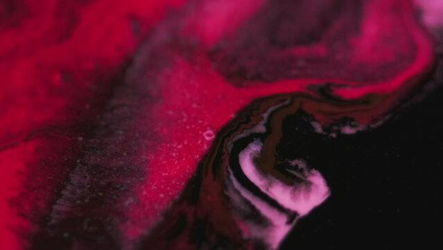 Paint splash. Ink mix. Defocused red pink black color shiny particles texture fluid emulsion blend flow dark abstract art background.