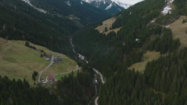 Saalbach-Hinterglemm, Austrian ski resort nestled in alpine trees, tilting up to reveal mountains, aerial view