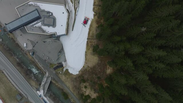 Saalbach-Hinterglemm (Austria) ski resort, surrounded by pine trees and snow patches, overcast day, aerial view