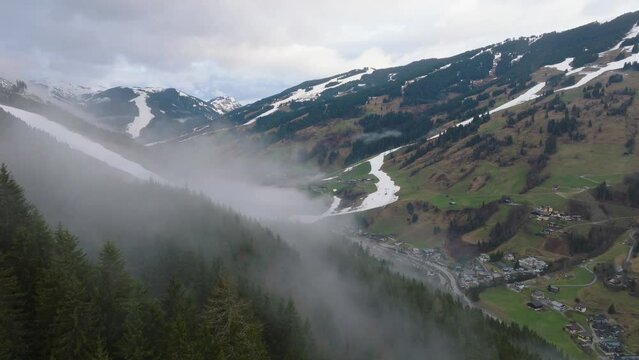 Saalbach-Hinterglemm (Austria) with fog over mountains and village at dusk, aerial view