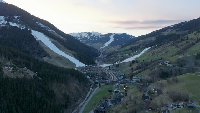 Saalbach-Hinterglemm ski resort in Austria during twilight, tilting down over the village, aerial view