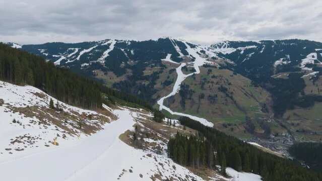 Mountainous winter landscape with patches of snow at Saalbach-Hinterglemm (Austria) ski resort, aerial view