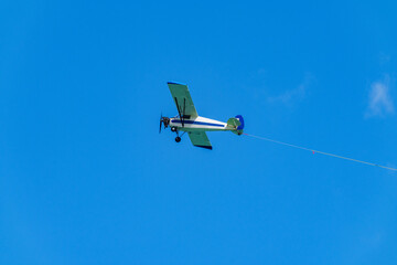 Aerial advertising banner airplane on a blue sky with visible ro - obrazy, fototapety, plakaty