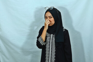 uncomfortable young Asian Muslim woman wearing hijab and black dress with white pattern feeling...