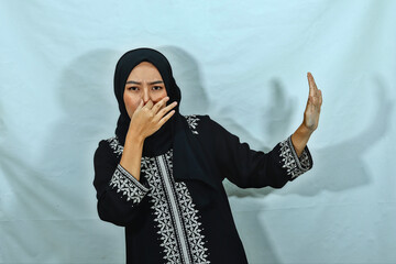 beautiful young Asian Muslim woman wearing hijab and black dress with white pattern holding her...