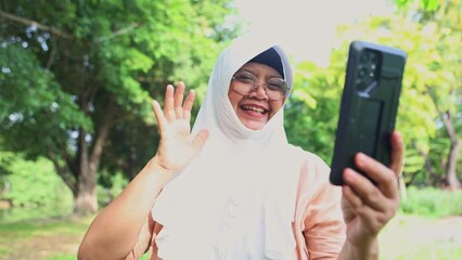 Muslim mother chatting with daughter using smartphone online technology live video call seeing each other's faces saying hello happy.