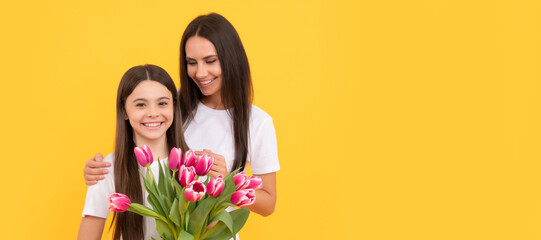 Mother and daughter child banner, copy space, isolated background. happy mother and daughter with spring tulip on yellow background.