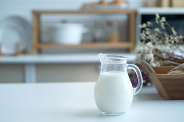 Pitcher of milk prepared for breakfast is placed near a basket of baked bread in the home kitchen,...