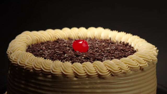 detail close up shot Mocha cake in a turn table with black background  mocca moka mochachino with shiny cherry on top fresh delicious tasty dessert party celebration