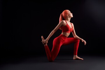 Young woman practicing yoga against black background
